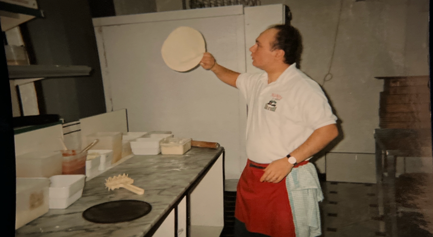 Gio making a pizza in a kitchen setting